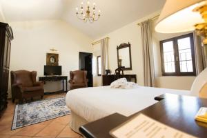 Schlafzimmer mit einem Bett, einem Schreibtisch und Stühlen in der Unterkunft Hotel Palacio de Hemingway in Ronda