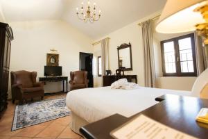 a bedroom with a bed and a desk and chairs at Hotel Palacio de Hemingway in Ronda