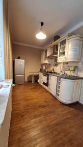 Il comprend une grande cuisine avec des placards blancs et un réfrigérateur. dans l'établissement AGAWA NOCLEGI, à Tarnów