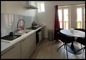 a kitchen with a sink and a table with chairs at Le Cocon in Saint-Quentin