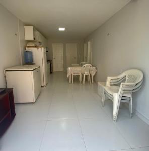 a kitchen with white tables and chairs and a refrigerator at Apartamento térreo no Morro Branco Marina II in Beberibe