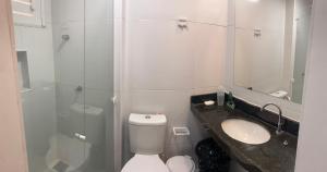 a white bathroom with a toilet and a sink at Apartamento térreo no Morro Branco Marina II in Beberibe +4 photos