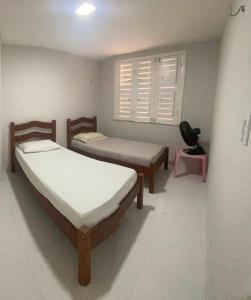 two beds in a room with a window at Apartamento térreo no Morro Branco Marina II in Beberibe
