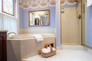 a bathroom with a tub and a sink and a mirror at The Oaks Victorian Inn in Christiansburg