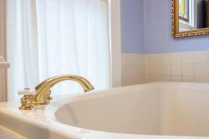 a bathroom with a white tub with a gold faucet at The Oaks Victorian Inn in Christiansburg