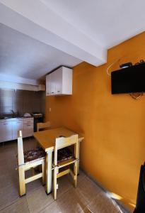 a kitchen with a table and two chairs and a television at Complejo Mayu Inti Wayra - Mayu Sumaj in Villa Icho Cruz