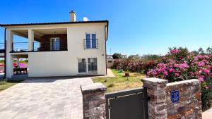 una grande casa bianca con cancello e fiori di Villa Leandra a Vodnjan (Dignano)