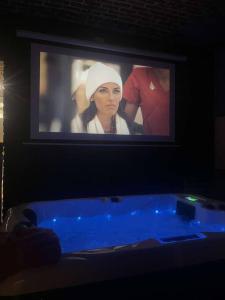 a tv screen with a woman on it and a tub at L’algéroise Home & Spa in Ronchin