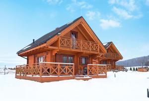 una cabaña de madera en la nieve en la nieve en Domki pod Czarną Górą en Idzików