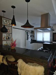 una cocina con encimeras negras y luces colgantes en Apartamento Alto Padrão Uruguaiana, en Uruguaiana