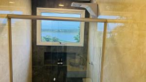 a bathroom with a shower with a window and a glass shower door at Suítes Costa Do Macacu-Garopaba in Garopaba