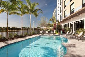 a swimming pool with palm trees and a building at Fairfield Inn & Suites by Marriott Wellington-West Palm Beach in Wellington