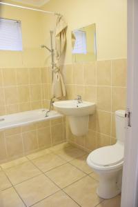 een badkamer met een toilet, een wastafel en een bad bij 303 Formosa in Kaapstad