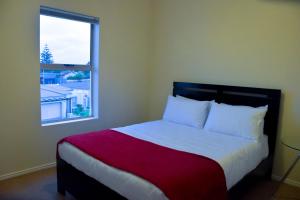 een slaapkamer met een bed met een rode deken en een raam bij 303 Formosa in Kaapstad