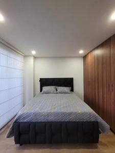 a bedroom with a large bed with a wooden wall at Aparment comfort deluxe cajica in Cajicá