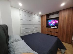 a bedroom with a bed and a flat screen tv at Aparment comfort deluxe cajica in Cajicá