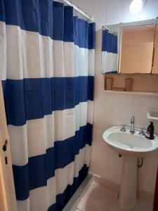 a bathroom with a sink and a blue and white shower curtain at Rent Ibera Nuñez in Buenos Aires