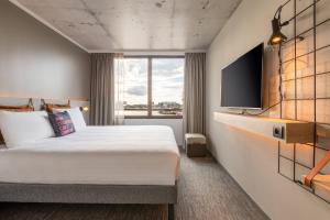 ein Hotelzimmer mit einem Bett und einem Flachbild-TV in der Unterkunft Moxy Bordeaux in Bordeaux