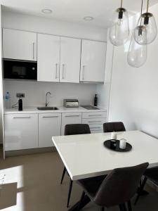 a kitchen with white cabinets and a white table and chairs at sky intempo resort & spa Benidorm apartment in Benidorm