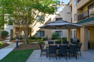 a patio with a table and chairs and an umbrella at Courtyard by Marriott Charlotte Matthews in Matthews