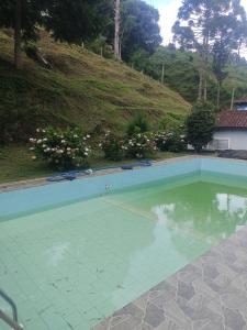 an empty swimming pool with a hill in the background at Pousada Uai vem ser feliz in Alagoa