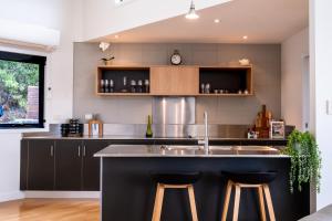 a kitchen with a sink and two bar stools at The Bolthole in Coles Bay