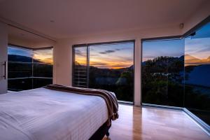 a bedroom with a bed and large windows at The Bolthole in Coles Bay