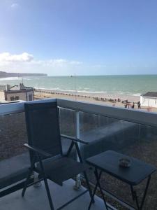 een stoel en een tafel op een balkon met een strand bij Idéal famille et couple , vue mer residence calme in Fécamp