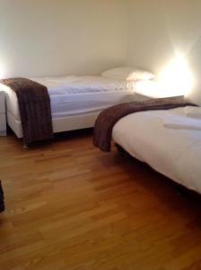 two beds in a room with wooden floors at Sólheimar Apartment in Húsavík