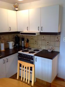 a kitchen with white cabinets and a stove top oven at Sólheimar Apartment in Húsavík