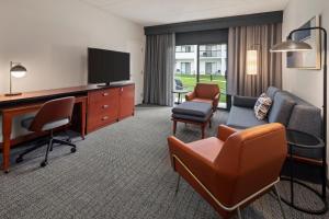 a hotel room with a desk and a tv and chairs at Courtyard by Marriott Chicago Waukegan / Gurnee in Waukegan