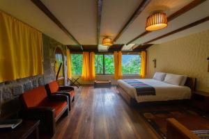 a bedroom with a bed and a couch and chairs at Bellavista Cloud Forest Lodge & Private Protected Area in Tandayapa