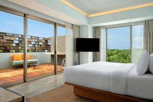 a bedroom with a large bed and a balcony at Aloft Bali Seminyak in Seminyak