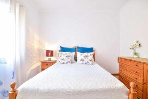 a bedroom with a large bed with blue pillows at Apartamento T2 com pátio e barbecue in Algoz