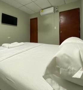 1 cama blanca grande en una habitación con TV en HOSTAL CASA PALMA, en Ríohacha
