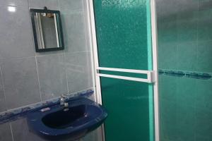 La salle de bains est pourvue d'un lavabo bleu et d'une douche. dans l'établissement Posada Brisas del Mar, à Bahía Solano