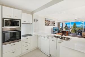 a kitchen with white cabinets and a counter top at Beachside Resort Kawana Waters in Buddina