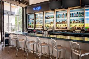 a bar with stools in a room with windows at aloft Green Bay in Green Bay