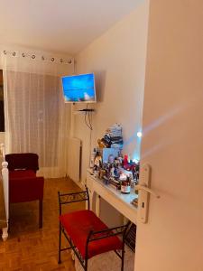 Zimmer mit einem Schreibtisch mit einem roten Stuhl und einem TV. in der Unterkunft Logement unique et chic PARIS 15 min champs Élysée in Rueil-Malmaison