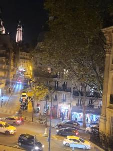 a busy city street at night with cars parked at Charmant appartement près de Montmartre in Paris