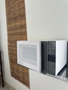 a microwave oven hanging on a wall at Suíte aconchegante com delicioso café da manhã in Porto Seguro