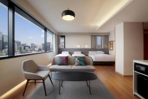 a hotel room with two beds and a chair at Moxy Seoul Insadong in Seoul