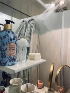 ein Badezimmer mit einer Flasche Seife und einem Spiegel in der Unterkunft Logement unique et chic PARIS 15 min champs Élysée in Rueil-Malmaison