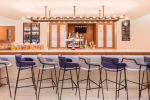 eine Bar in einem Restaurant mit Hockern in der Unterkunft Courtyard by Marriott Glasgow Airport in Paisley