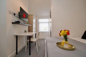 a room with a desk and a table with a vase of flowers at Gordon House - 4Bed Coventry City Centre Oasis with Free Parking in Coventry