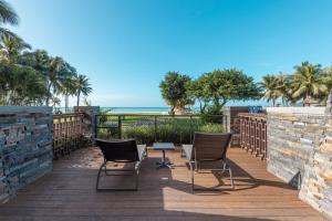 una terraza con sillas, una mesa y el océano en Sheraton Shenzhou Peninsula Resort en Wanning