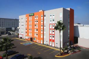 ein orangefarbenes und weißes Gebäude mit einem Parkplatz in der Unterkunft City Express Junior by Marriott Tijuana Otay in Tijuana