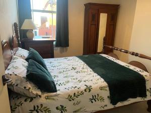 uma cama com um cobertor verde e almofadas em Two bed flat in popular York Rd em Birmingham