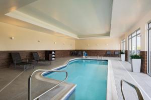 einen Pool in einem Hotel mit Stühlen und Tischen in der Unterkunft Fairfield Inn & Suites by Marriott Lincoln Airport in Lincoln