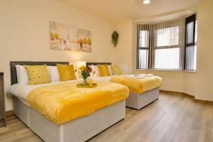 een slaapkamer met 2 bedden met gele lakens bij Matlock Studio 2 – Coventry in Coventry